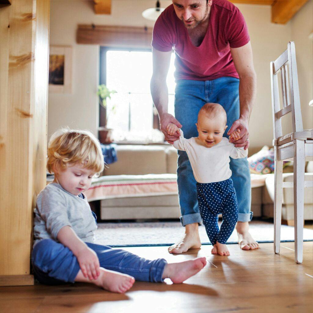 Father with two toddlers at home. First steps.